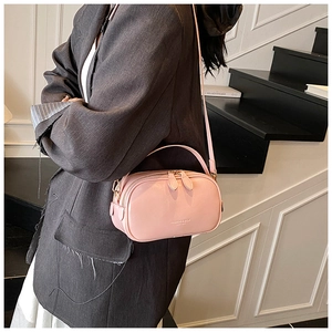 Pink oil wax leather crossbody bag detail with embossed text and dual zippers