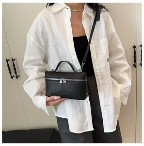 Detail of black lychee grain leather vanity bag with silver hardware and top handle strap