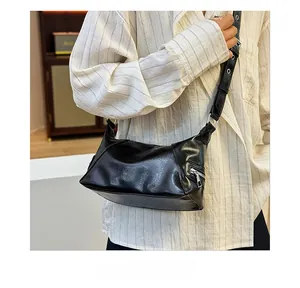 Close-up of black leather tote bag with silver zipper and adjustable strap details