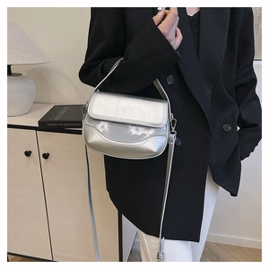 Detail of silver metallic saddle bag styled with a black suit and modern home decor