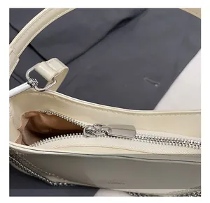 Close-up of polished cream patent leather handbag with silver metal zipper and hardware