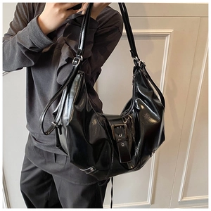 Detail of black glossy crescent tote bag with metal buckle and adjustable straps