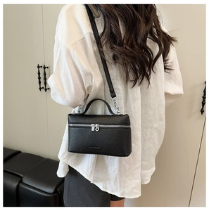 Detail view of black lychee grain leather crossbody bag with dual silver zippers