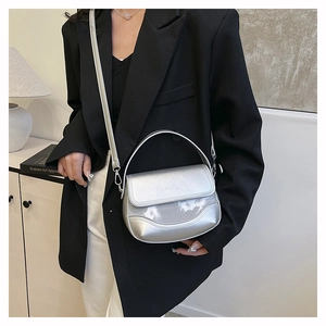 Detail showing metallic silver saddle bag with wave stitching and glossy finish on model