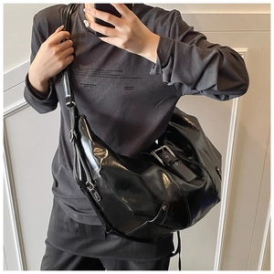 Detail of black glossy patent leather moon bag with metal buckle and adjustable strap