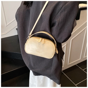 Detail view of the cream leather crossbody bag with dual zippers and top handle