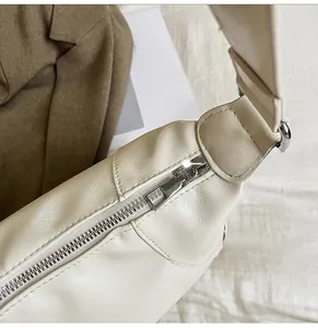 Close-up of metal zipper detail and grain texture on beige leather tote bag
