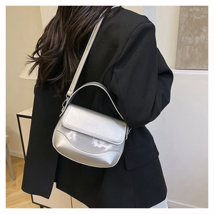Detail of silver metallic saddle bag with fold-over flap and slim shoulder strap