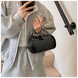 Detail of black oil wax leather handbag featuring glossy finish and double zipper closure
