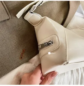 Detailed close-up of cream white PU leather bag side zipper and litchi texture
