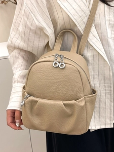 Elegant beige lychee textured leather backpack with silver zippers worn by a model