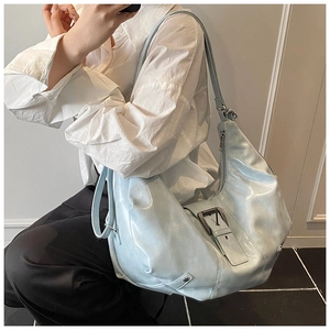 Macro detail of a light blue distressed leather tote bag with large decorative buckle strap