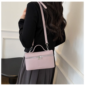 Pink litchi grain leather crossbody bag shown on model with dual zipper detail