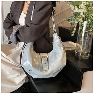 Detail of light blue hobo bag with metallic finish and decorative large belt buckle