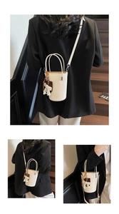 Detail view of cream mini bucket bag with woven tassel pendant and adjustable crossbody strap