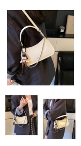 Detail of cream crescent shoulder bag with silver chain, leather strap and doll charm