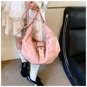 Close-up of pink glossy Hobo bag with adjustable strap and silver metal buckle detail