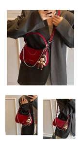 Close-up of red patent leather bag with silver chain strap and cute bear charm accessory