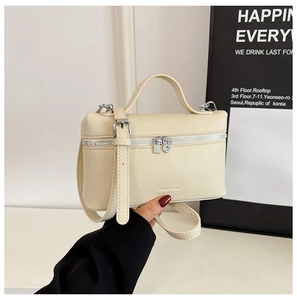 Close-up of cream lychee pattern leather handbag with silver zipper and top handle