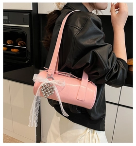 Detailed view of pink glossy patent leather cylinder bag with lace bow and heart charm