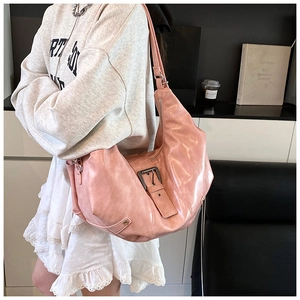 Detail of pink semi-circle tote bag featuring vintage metal buckle on a wide shoulder strap