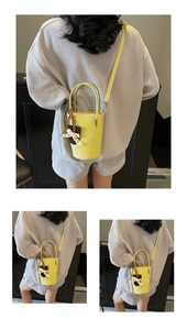 Detail of a bright yellow mini bucket bag featuring a lace bow charm and adjustable strap