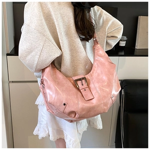 Detail of vintage pink leather hobo bag with buckled straps and metallic stud accents