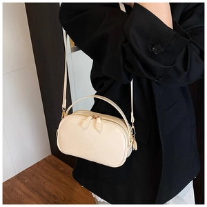 Close-up of beige crossbody pillow bag with dual zippers and leather handle detail