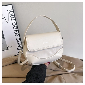 Detail of a cream leather saddle bag with top handle and adjustable shoulder strap