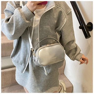 Detail of silver metallic handbag with top handle and white leather shoulder strap