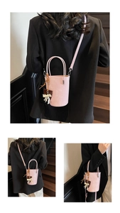 Detailed side view of pink bucket bag with leather texture and cute bow ornament