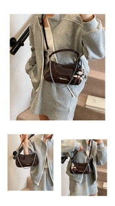 Detailed close-up of dark brown patent leather crescent bag with chain and doll charm