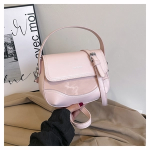 Detail of pink leather saddle bag featuring metal logo and adjustable shoulder strap