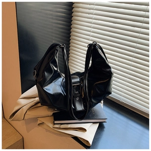 Detail of black glossy leather tote bag with vintage metal buckles and adjustable strap