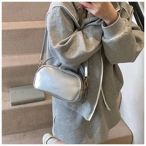 Detail of silver oil wax leather crossbody bag with dual zippers and fashion text