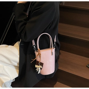 Pink bucket bag detail with elegant white lace bow and brown leather tag charm