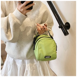 Lifestyle shot of light green casual nylon bag with Lucky tag and black handles
