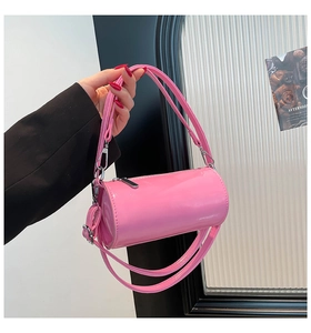 Detail einer glänzenden rosa Lackleder-Zylindertasche mit silbernen Metallteilen und Gurt