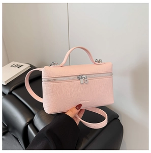 Detailed macro view of pink litchi grain leather handbag with silver zippers and strap