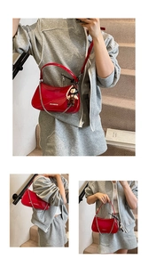 Red patent leather handbag detail featuring silver chain and doll pearl pendant accessory