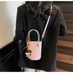 Detail view of pink bucket bag with lace bow charm worn by model on stairs
