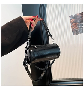 Detail einer kleinen schwarzen zylindrischen Handtasche aus glänzendem Lackleder