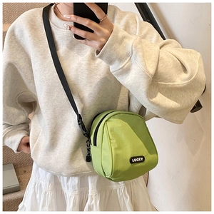 Detailed close-up of a grass green nylon crossbody bag with LUCKY label and black strap