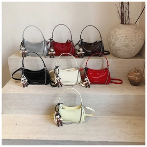 Detail view of colorful patent leather half-moon bags with silver chain straps and charms