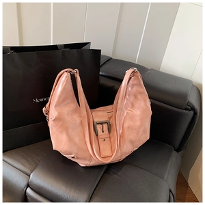 Macro shot of peach pink leather tote bag featuring a vintage metal buckle and texture