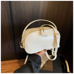 Detail view of cream white oil wax leather square bag with double zippers and gold lettering