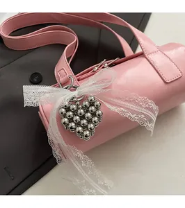 Detail of pink cylindrical handbag with silver heart beads and lace bow decoration