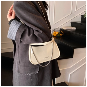 Detail of a creamy white patent leather underarm bag with silver chain and logo