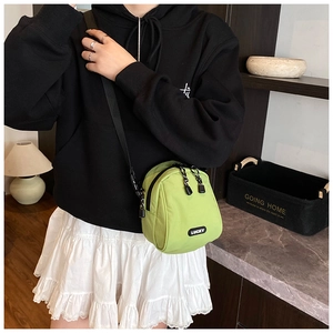 Close-up of light green nylon crossbody bag with Lucky label and adjustable black strap