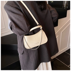Detail of cream patent leather baguette bag with silver chain and adjustable shoulder strap
